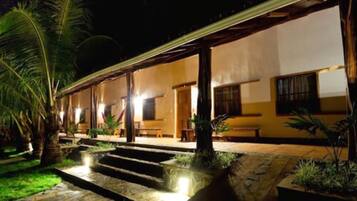 A building with a covered outdoor area, steps leading to the entrance, and palm trees.