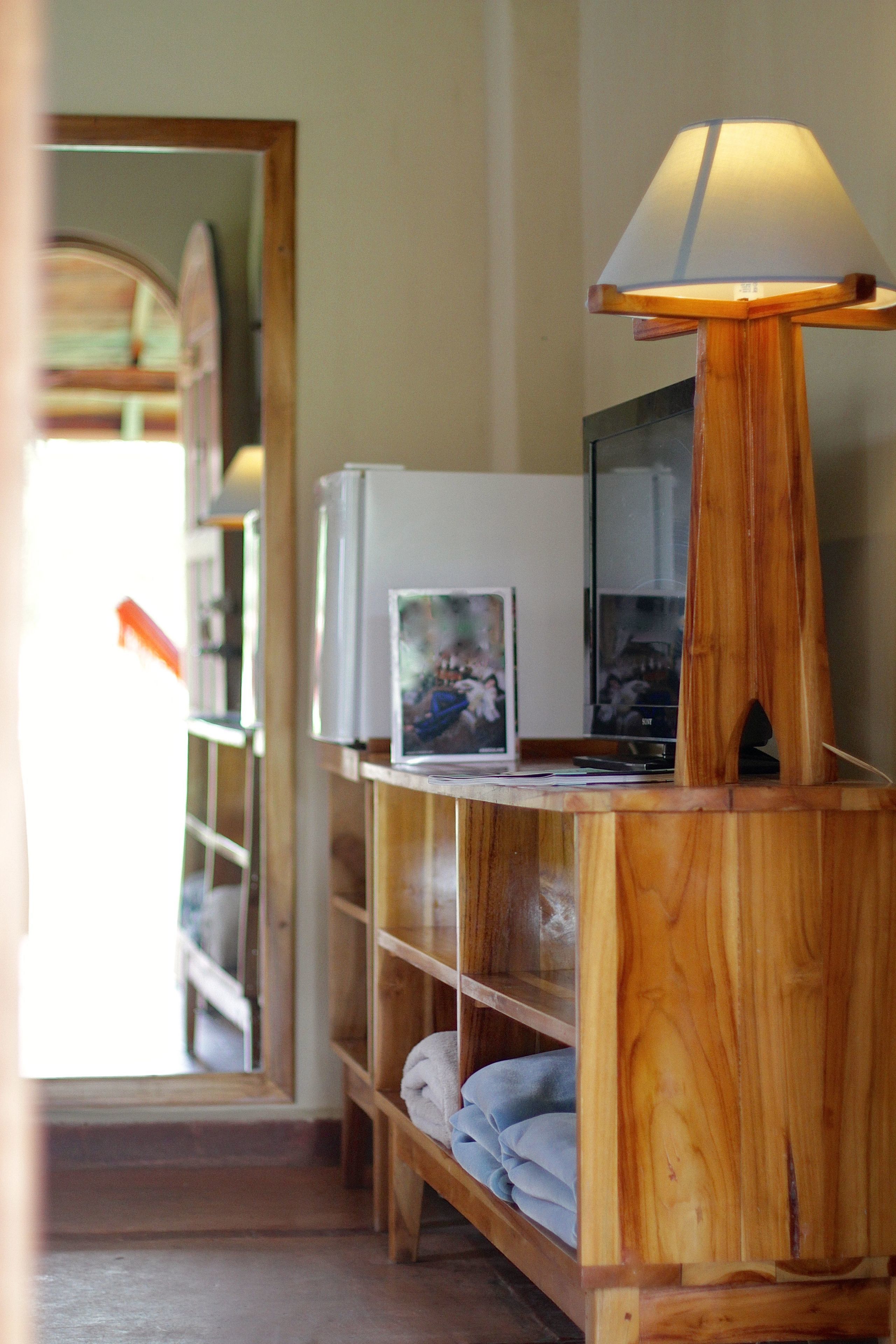 A wooden shelf with a lamp, a framed picture, and a television.