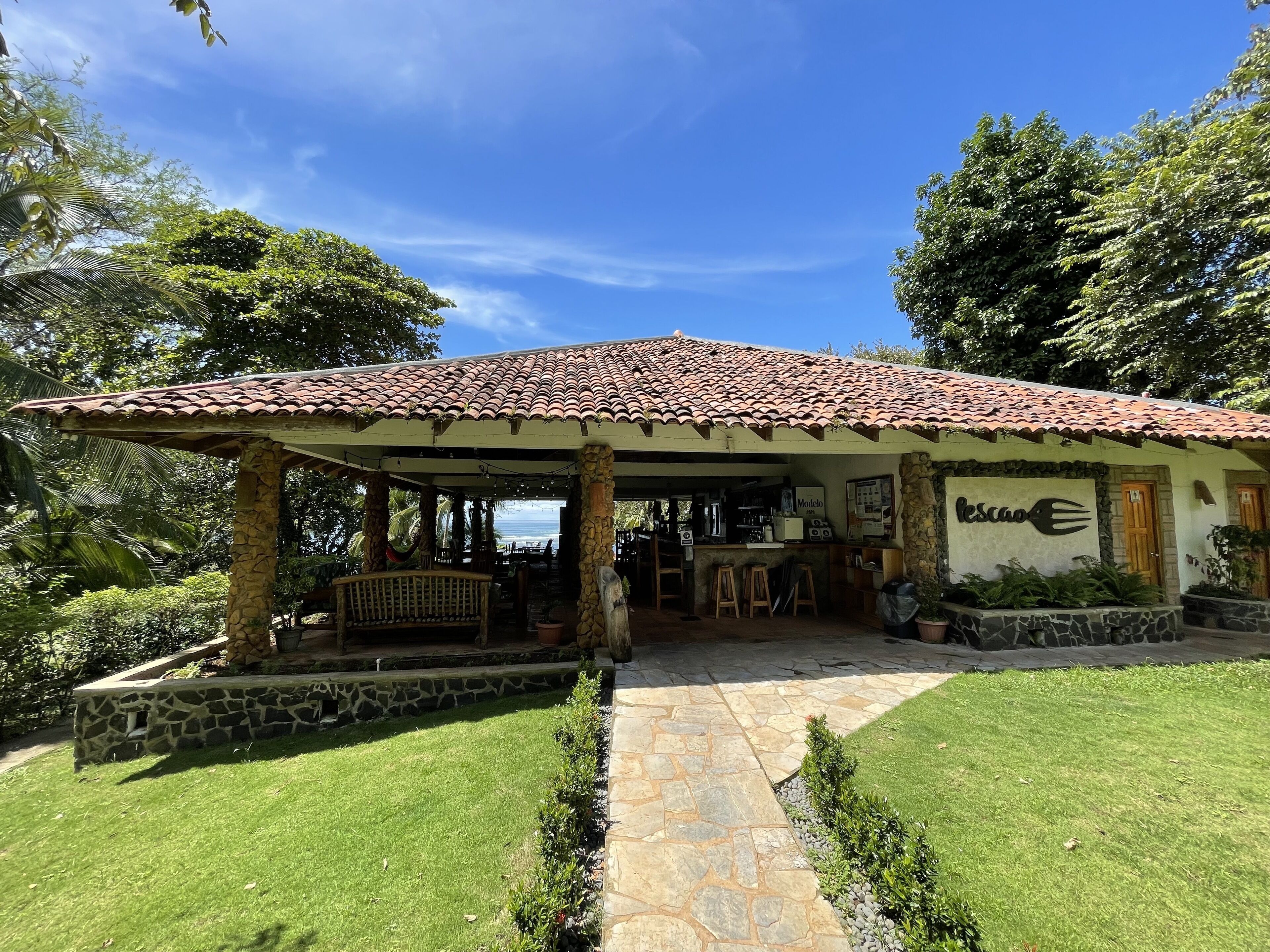 A covered outdoor seating area with a stone pathway leading to a bar.