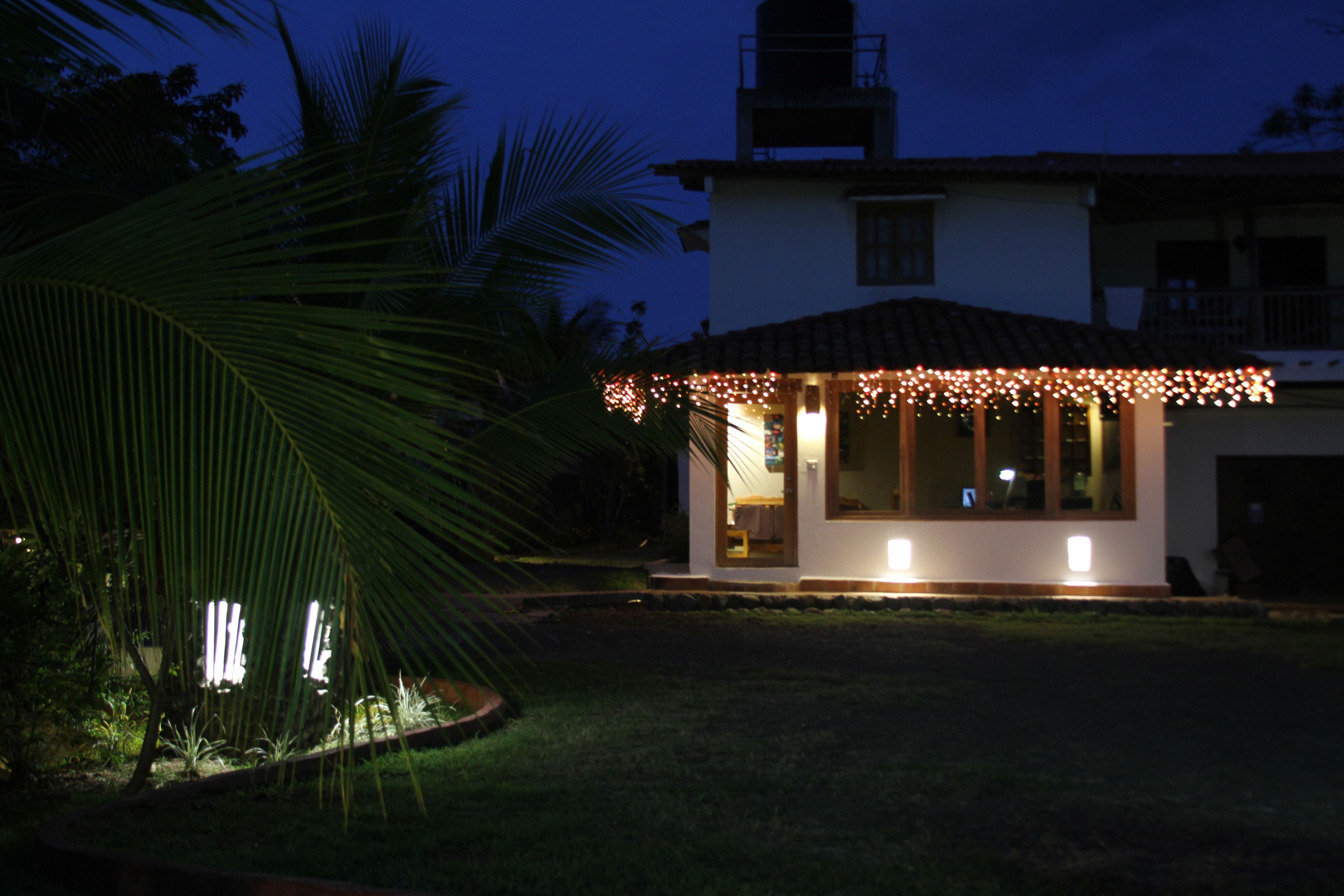 A house with a covered patio area, surrounded by a well-maintained lawn and palm trees.