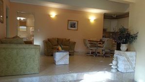Un salon comprenant un canapé, une table basse et un coin repas avec des chaises et une table. Un escalier mène à un autre niveau.