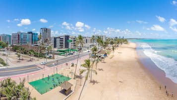 A beachside cityscape with a wide road, palm trees, and a beach.
