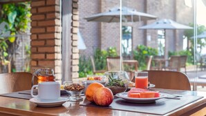 A breakfast table with a coffee pot, fruit, and a glass of juice. - Cais da Praia Hotel (Maceió)