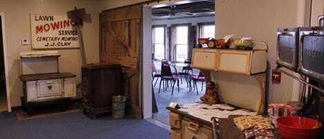 Una habitación con muebles antiguos, un cartel de servicio de corte de césped y vistas a otra sala con sillas.