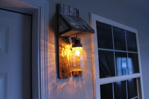 A rustic wall-mounted light fixture with a mason jar design, mounted on a wooden board against a wall.