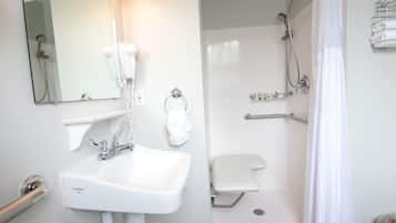 A bathroom with a sink, mirror, towel rack, shower, and toilet.