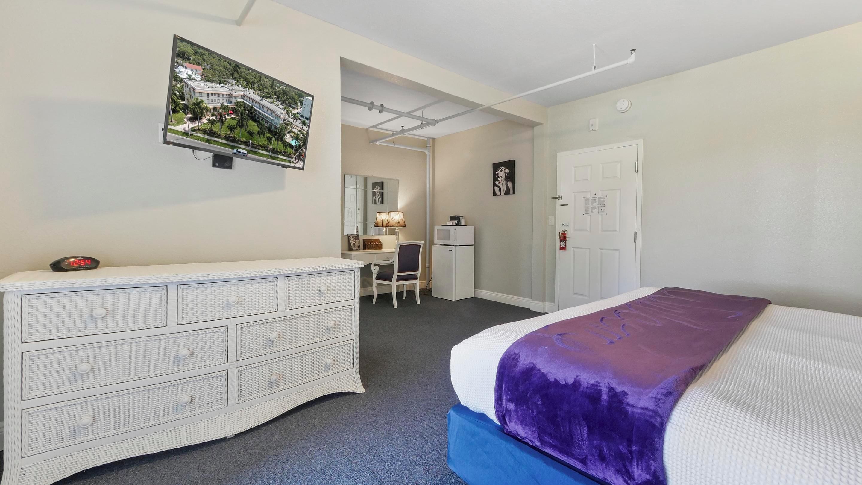 A bedroom with a bed, a dresser, a desk, a chair, and a door.