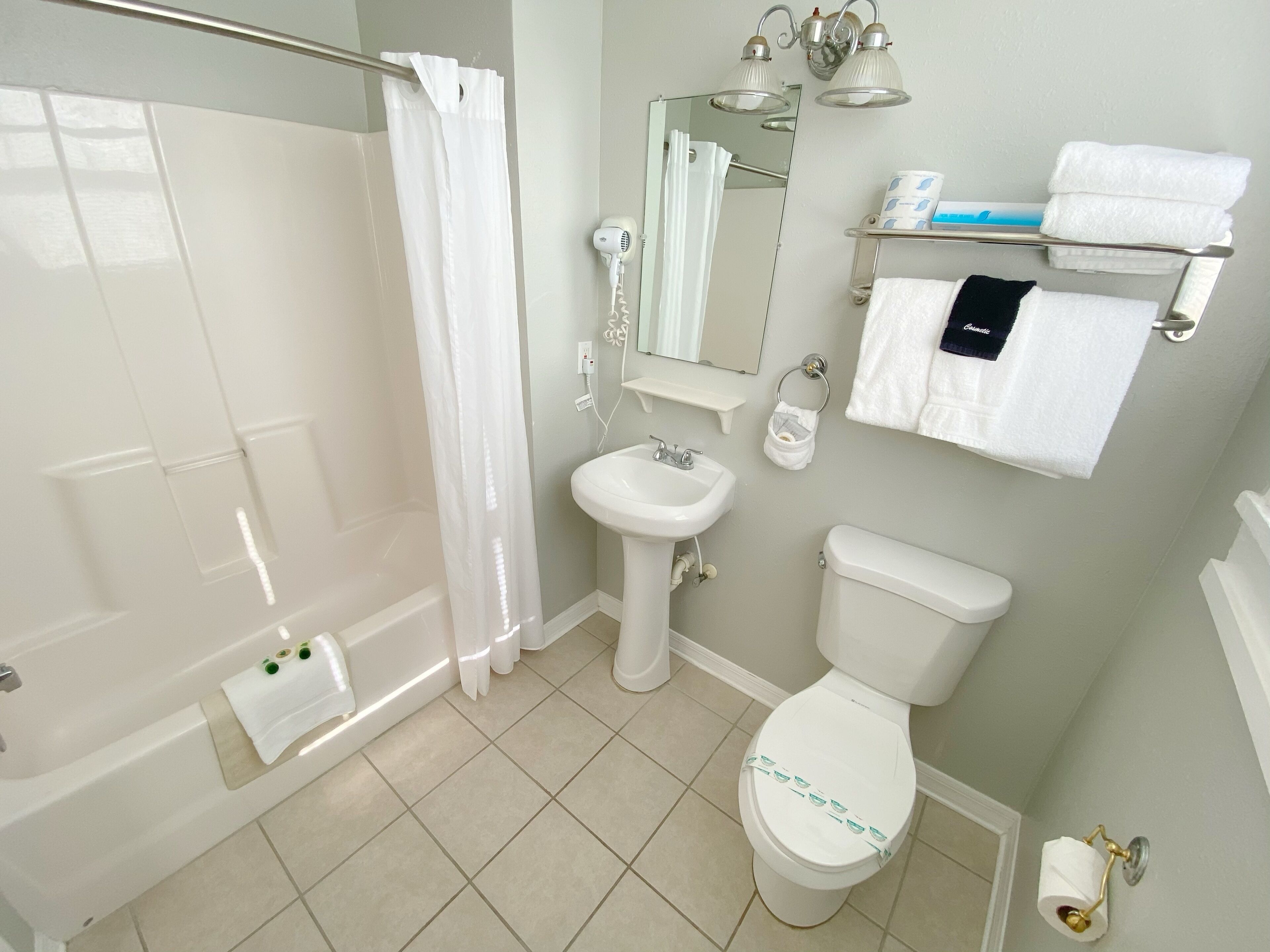 Een badkamer met een bad, een wastafel, een toilet, een spiegel en een handdoekrek met handdoeken.