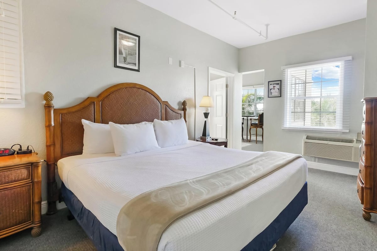Une chambre d’hôtel bien aménagée, avec un grand lit, une tête de lit en bois, des tables de chevet, un bureau et une chaise.