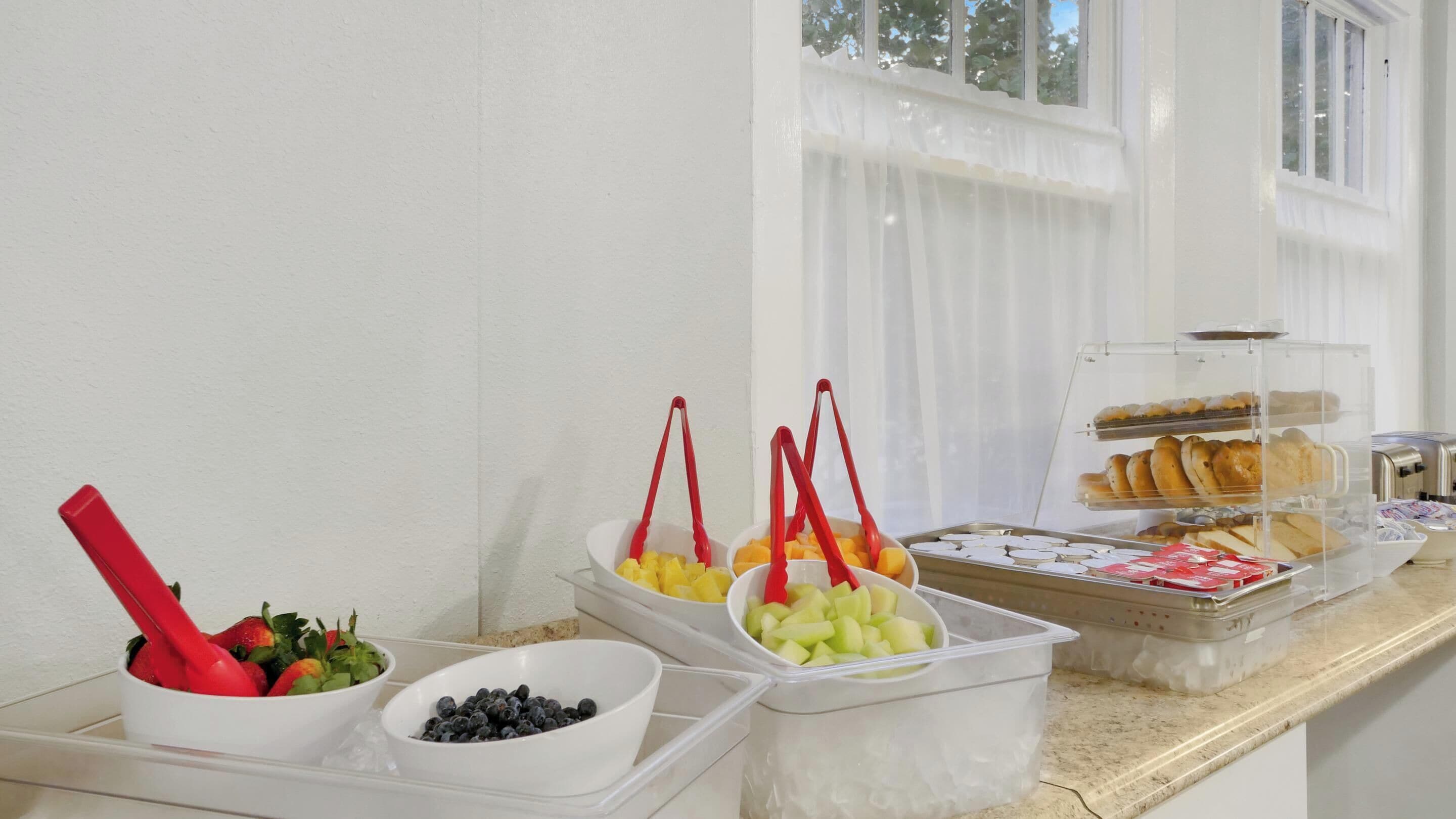 A breakfast buffet with various fruits and pastries.