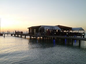 A pier with outdoor seating areas and a covered section, overlooking calm water. - Flamboyant Garden Villas (Oranjestad)