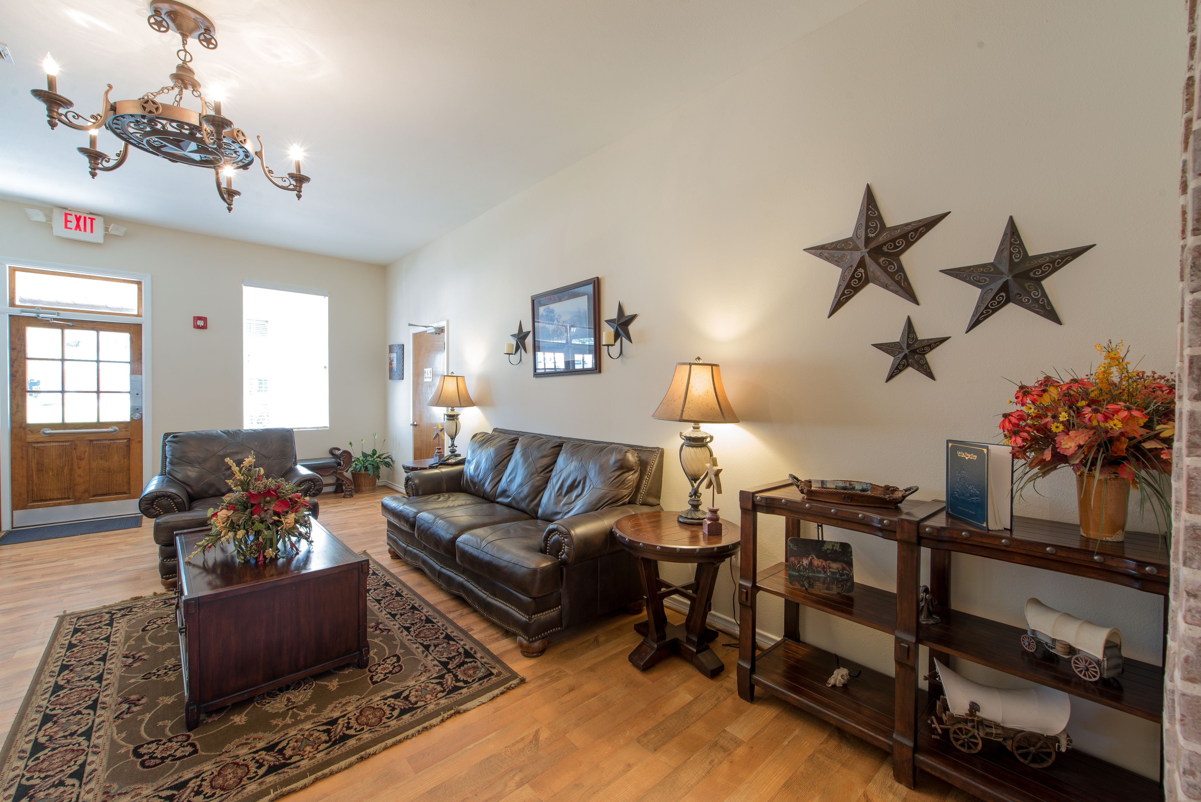 A living room with a leather sofa, a coffee table, a chandelier, and a wall decorated with stars.