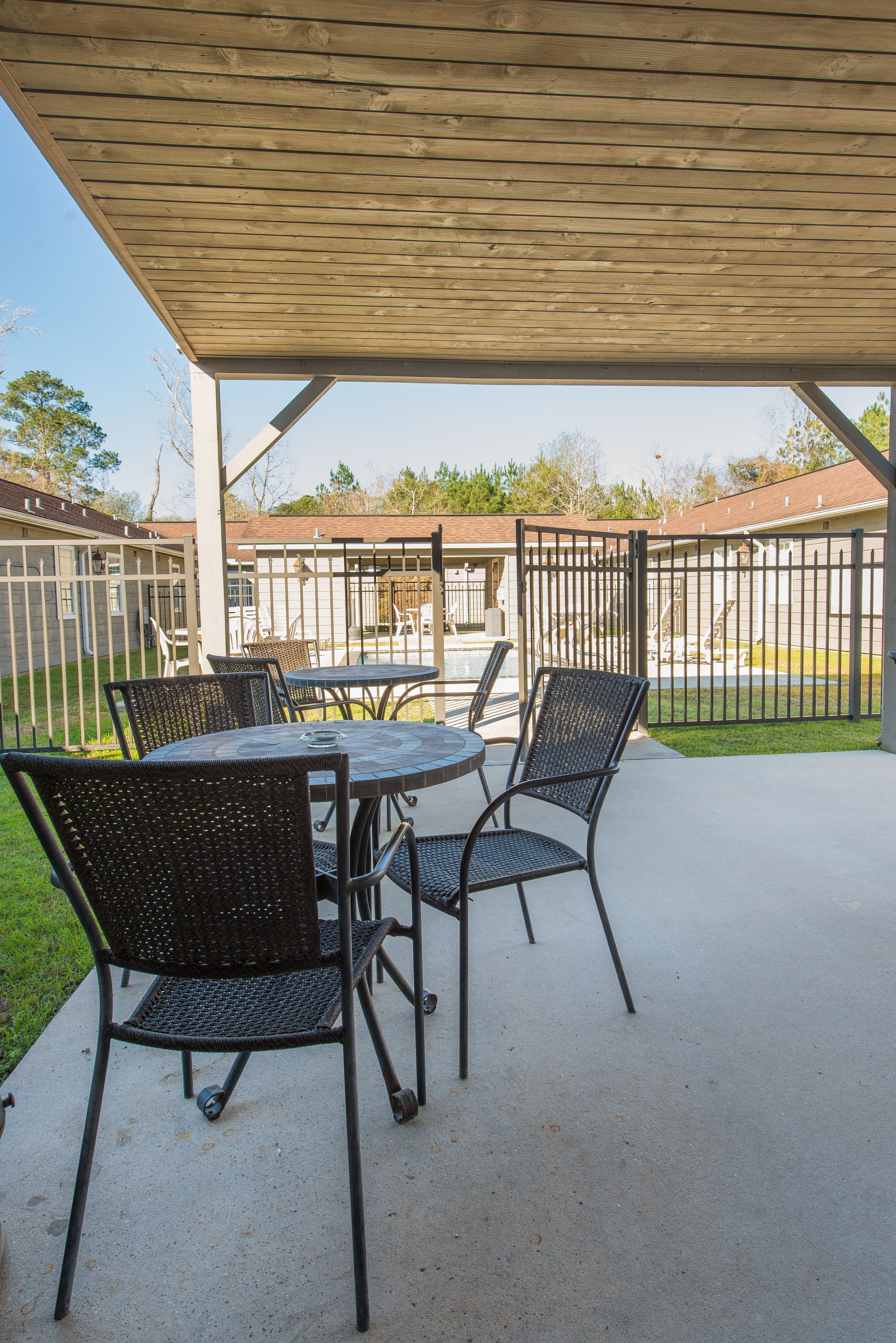 An outdoor patio with a covered seating area, a pool, and a fenced yard.