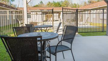 An outdoor patio with a covered seating area, a pool, and a fenced yard.