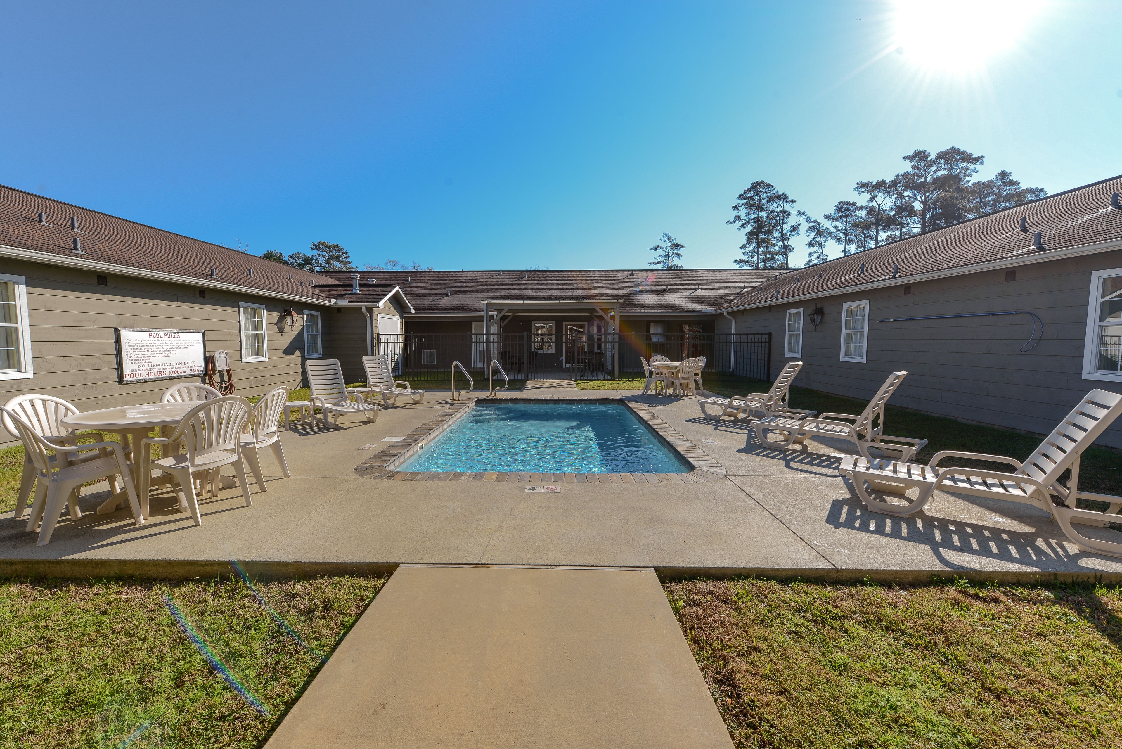A pool area with lounge chairs and a signboard.