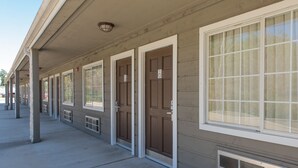 A row of motel rooms with individual doors and windows, a covered walkway, and a vent on the exterior wall. - The Stagecoach Inn of Woodville (Woodville)