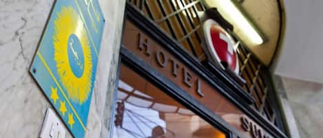 Un letrero de hotel con un diseño de sol y estrella, un emblema rojo y blanco, y la palabra 'HOTEL' en grande.