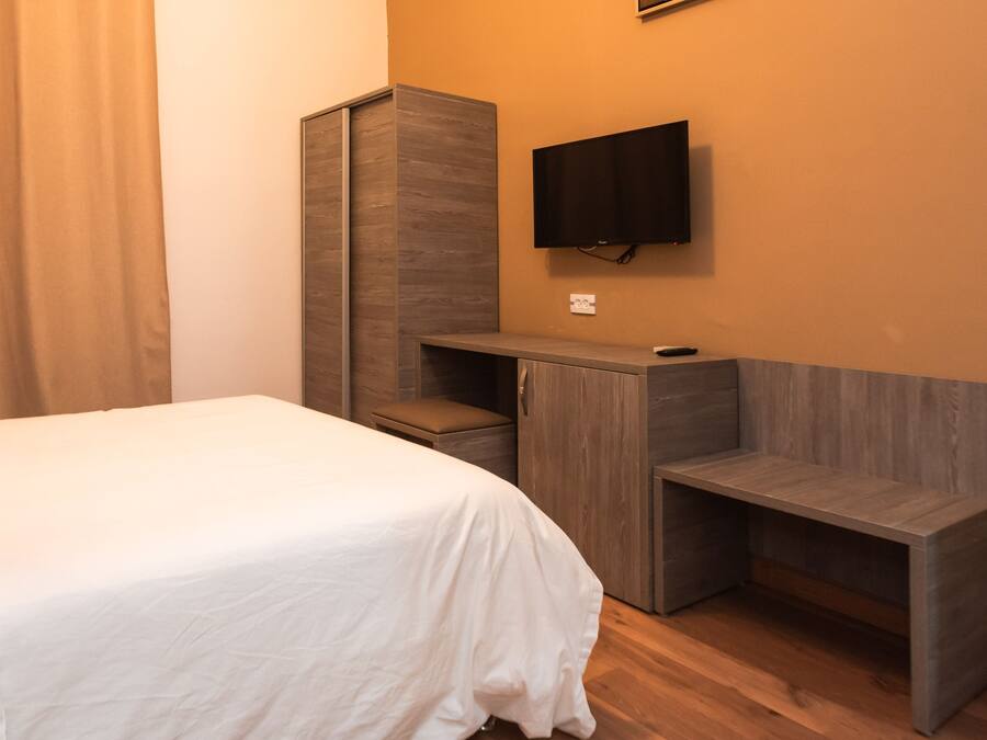 A bedroom with a bed, a desk, and a TV mounted on the wall.