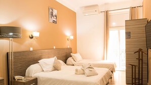 A hotel room with two beds, a bedside table with a lamp, a wall-mounted air conditioner, and a wooden wardrobe. - Hôtel Suisse (Algiers)