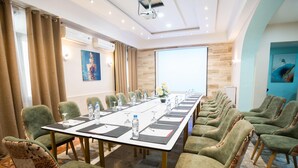 A conference room with a long table, green upholstered chairs, and a projector screen. - Hôtel Suisse (Algiers)
