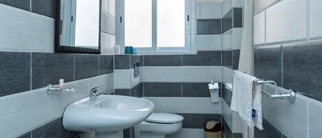 A bathroom with a sink, toilet, and window.
