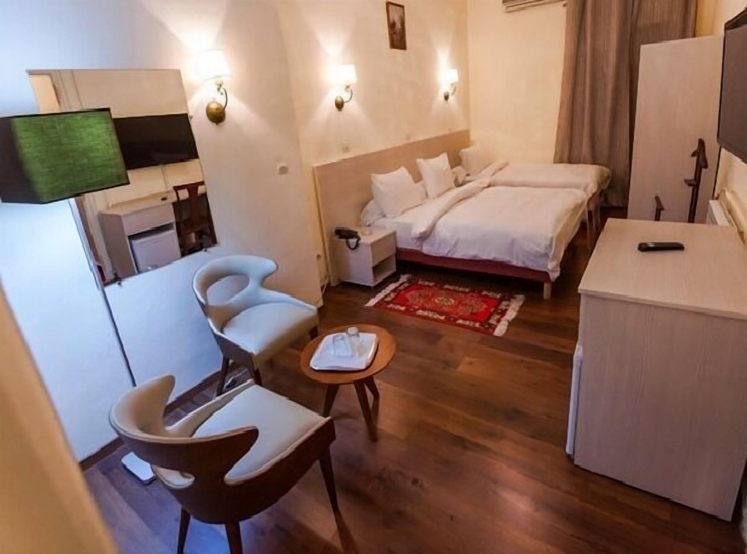 Una habitación de hotel con una cama, un escritorio, una silla, un televisor y una mesita con un libro.