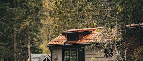 Eine Holzhütte mit einer Holzterrasse, einem Feuerkorb und Sitzgelegenheiten im Freien.