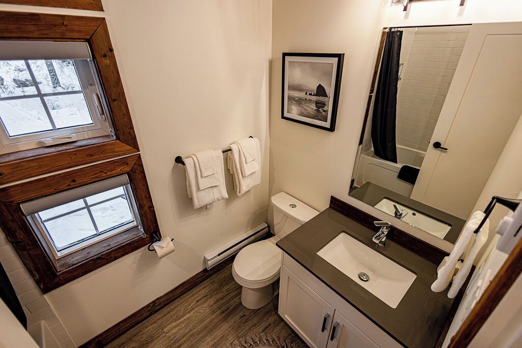 A bathroom with a window, a toilet, a sink, and a mirror.