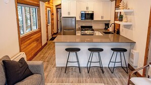 Una cocina moderna con armarios blancos, una isla central con taburetes y techo de madera.