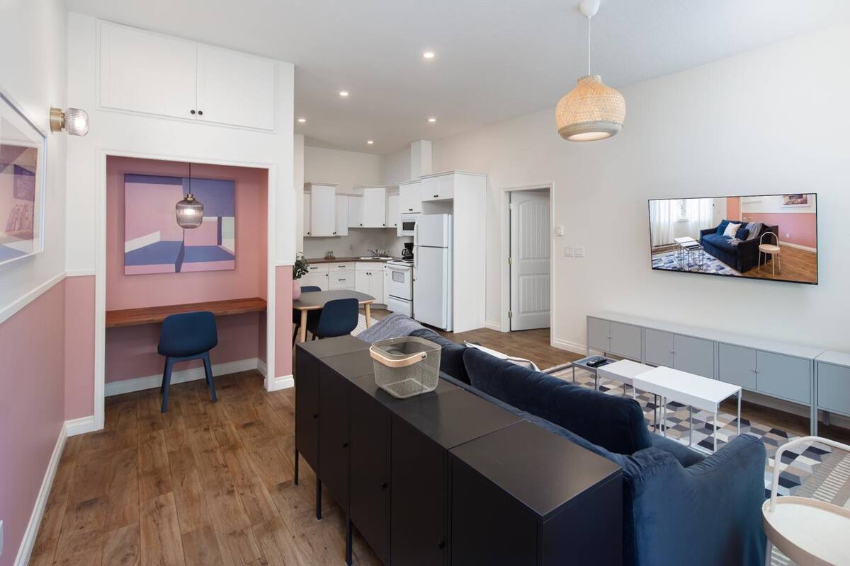 Un apartamento moderno con cocina, comedor y sala de estar. Incluye un sofá, una mesa de comedor y un televisor montado en la pared.