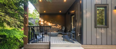 A modern building with a wooden deck, outdoor seating, and a large window.
