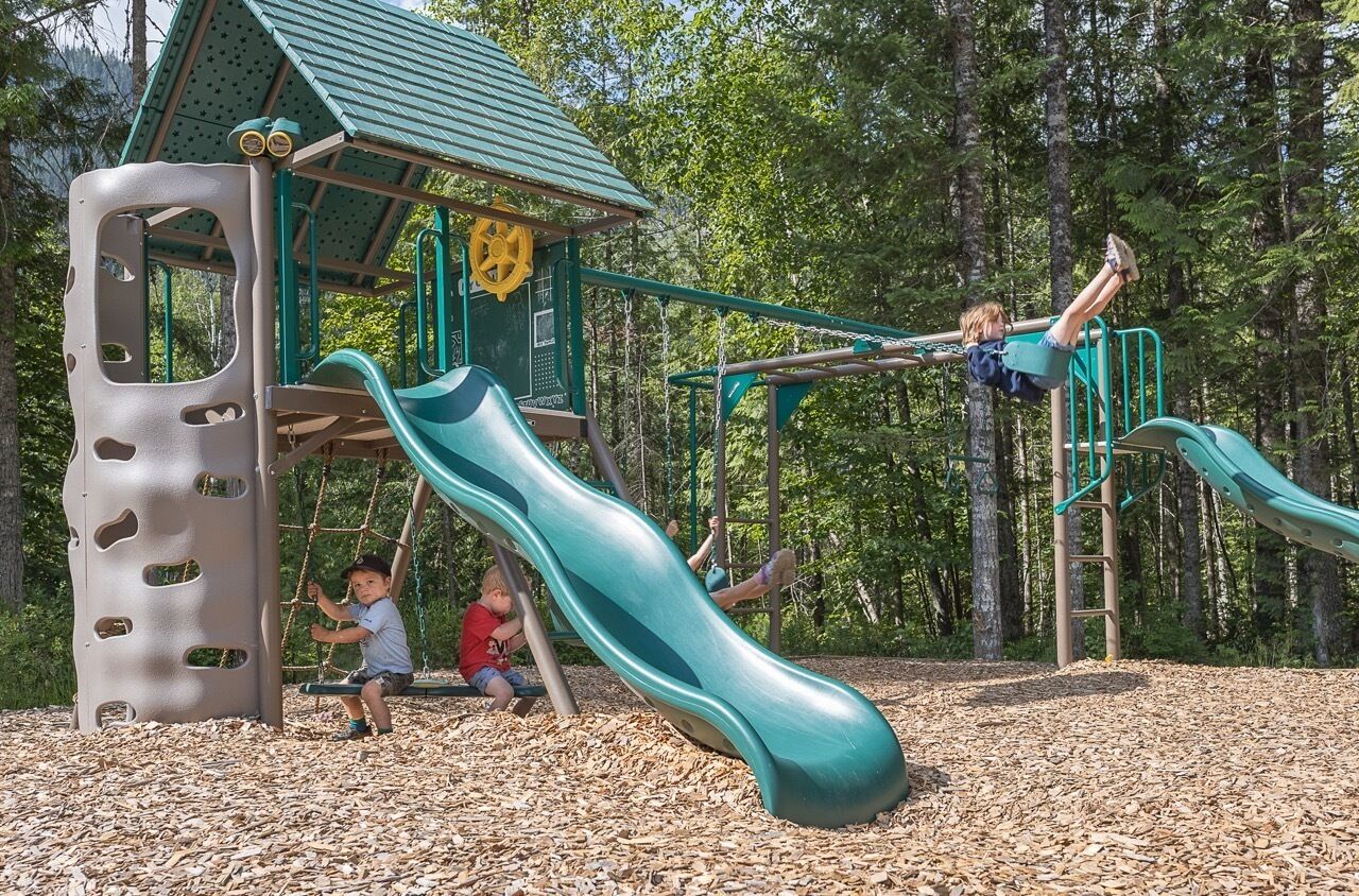 A playground with a slide, climbing structures, and a small shelter.
