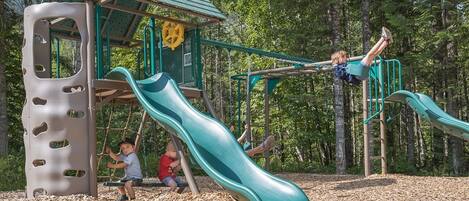 A playground with a slide, climbing structures, and a small shelter.