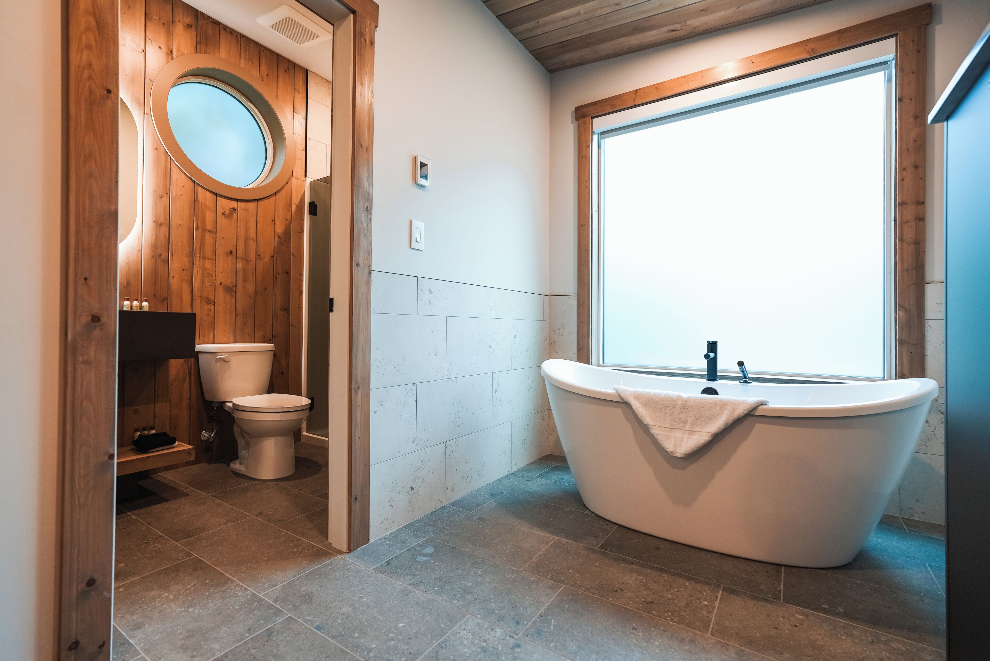 Un baño con una bañera independiente, un inodoro y un tocador de madera.