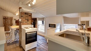 A kitchen with a brick wall, a stove, a microwave, and a sink. - White's Corner (Bothwell)