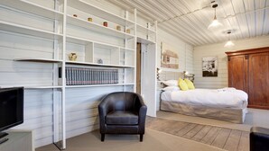 A room with a bed, a black leather chair, a bookshelf, and a television. - White's Corner (Bothwell)