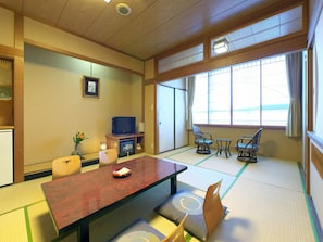 Una habitación tradicional japonesa con suelo de tatami, una mesa baja y un televisor.