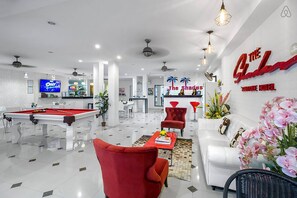 A modern hotel lobby with a pool table, red chairs, a white sofa, and a reception desk. - The Shades Boutique Hotel Patong Phuket (Patong)