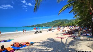 A beach with people sunbathing, umbrellas, and beach chairs. - The Shades Boutique Hotel Patong Phuket (Patong)