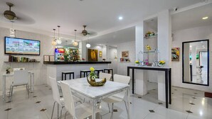 A modern dining area with a white marble table, clear chairs, and a bar with shelves of bottles. - The Shades Boutique Hotel Patong Phuket (Patong)