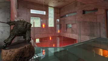 A modern interior with a glass railing, a wooden sculpture, and a red-lit area.