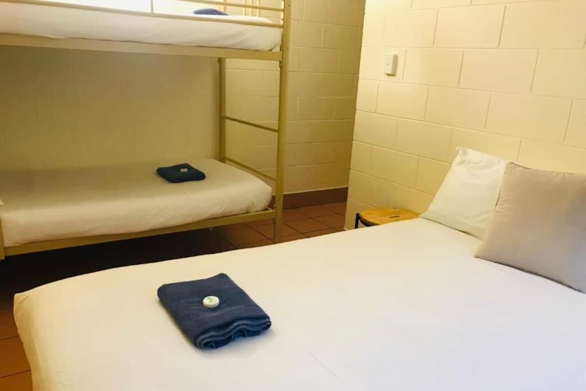 A bunk bed room with a white mattress and a single bed with a white pillow.