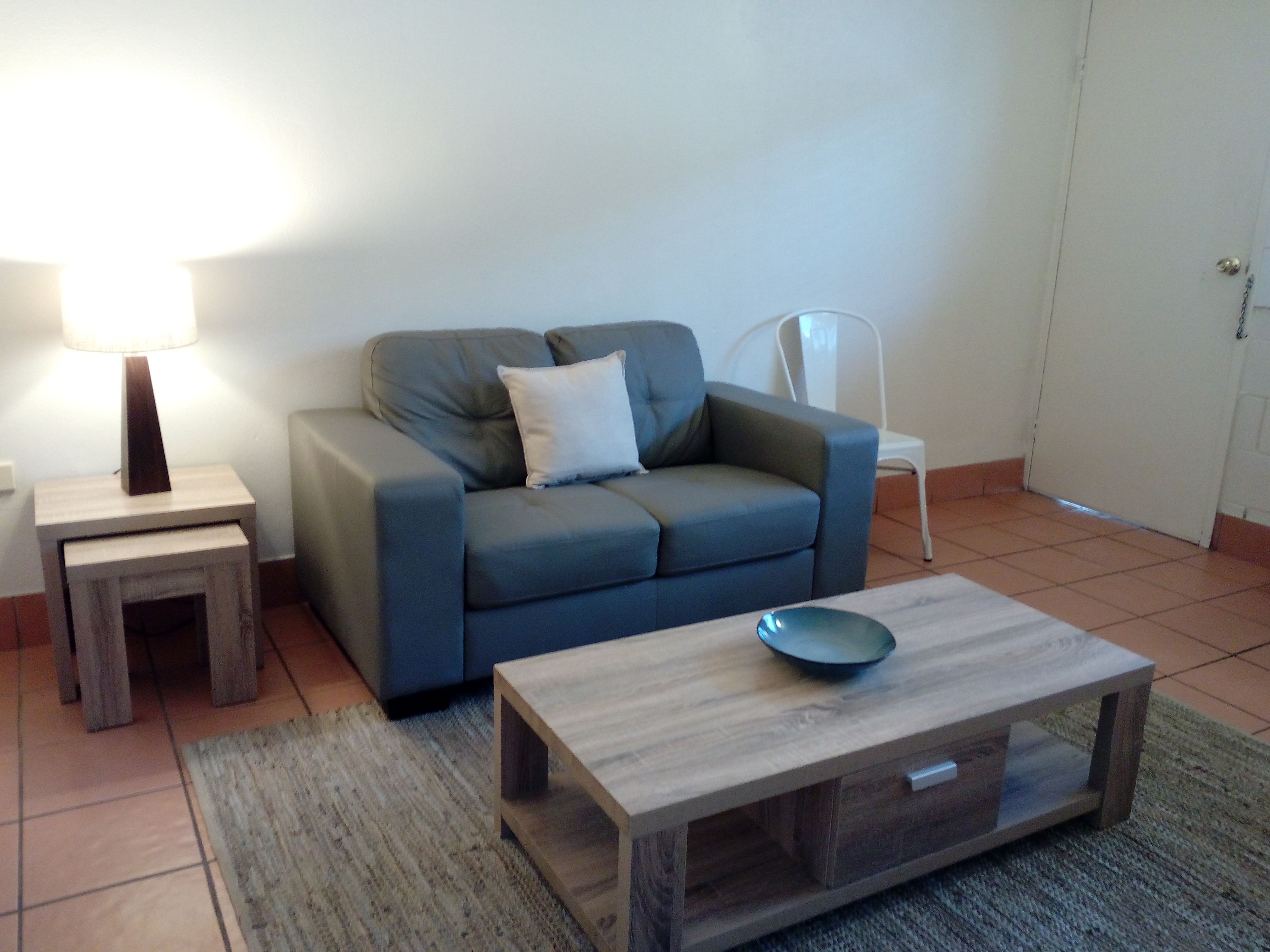 A living room with a sofa, a coffee table, a lamp, and a chair.