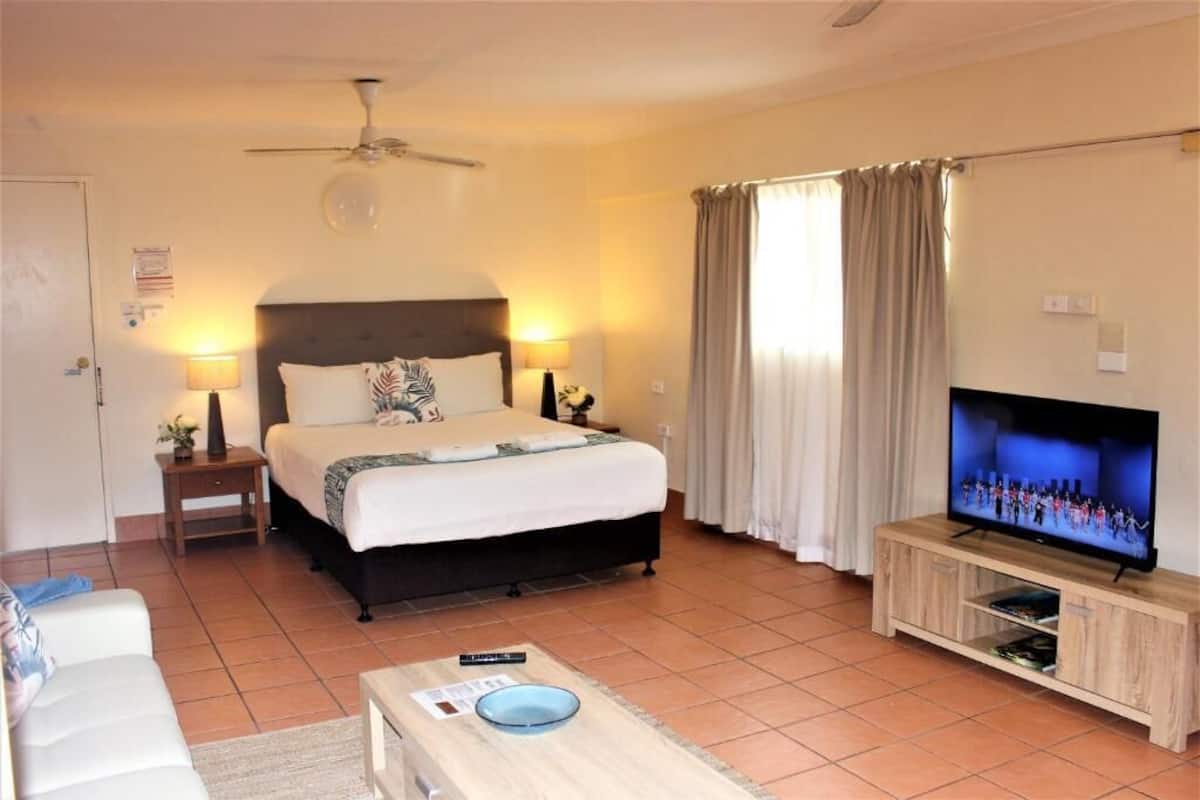 A hotel room with a bed, a television, a small table, and a sofa.