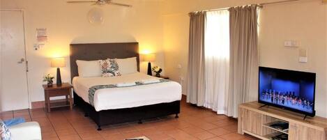 Una habitación de hotel con una cama, televisión, una mesita y un sofá.