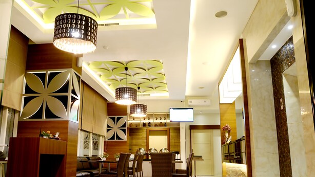 Un comedor moderno con techo alto, iluminación decorativa y una televisión de pantalla plana.