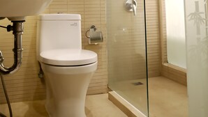 A bathroom with a toilet, sink, and glass-enclosed shower. - Biz Boulevard Hotel (Manado)