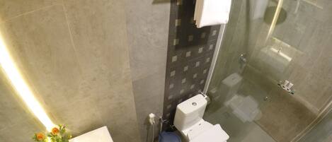 A modern bathroom with a glass-enclosed shower, a white toilet, and a sink with a vase of flowers.