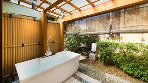 Una bañera independiente en un espacio exterior cubierto con un porche de madera.