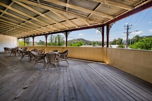 A covered outdoor area with wooden flooring and wicker furniture. - Peel Inn Nundle (Nundle)